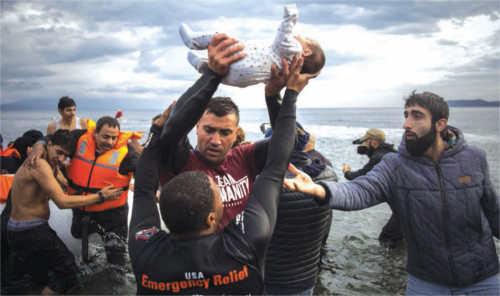 Volunteers assist refugees who traveled in a dinghy from Turkey to the Greek island of Lesbos in November. Santi Palacios/AP