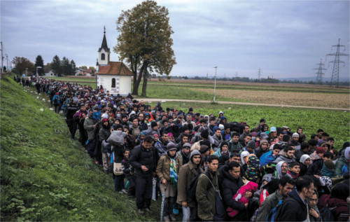 Migrants escorted by riot police walk in October to a camp outside Dubova, Slovenia, to register as refugees. Sergey Ponomarev/ The New York Times