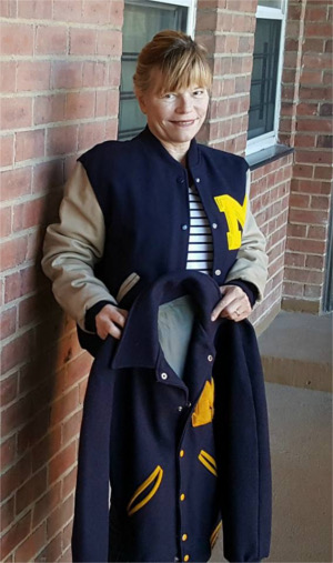 Patricia Kranz holds her old University of Michigan varsity letter jacket while wearing a new one that features proper school colors and design.
